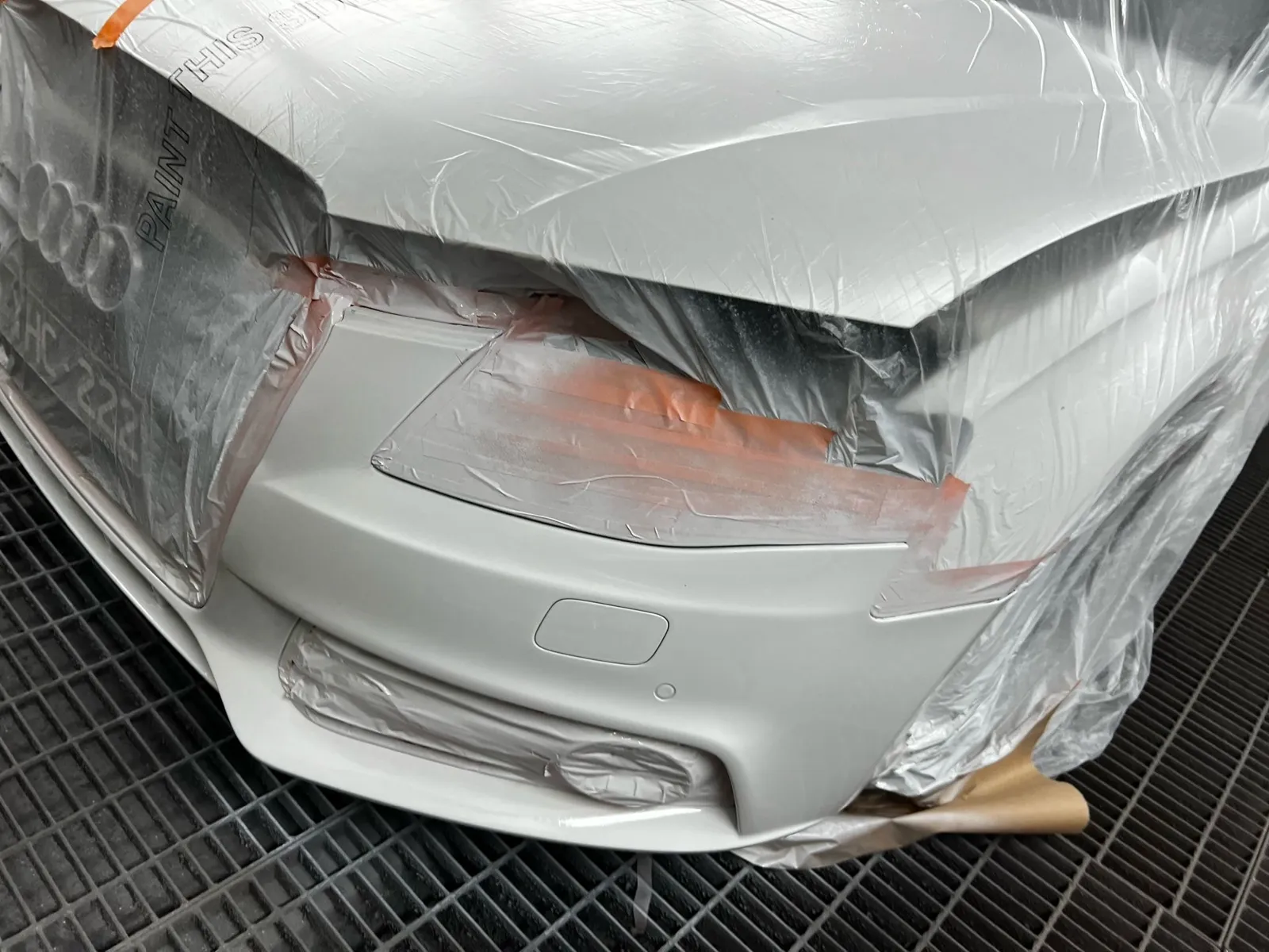 Silver front bumper masked and primed for paint in the spray booth